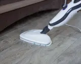 Mop parowy Vileda czyści drewnianą podłogę, wydzielając parę.