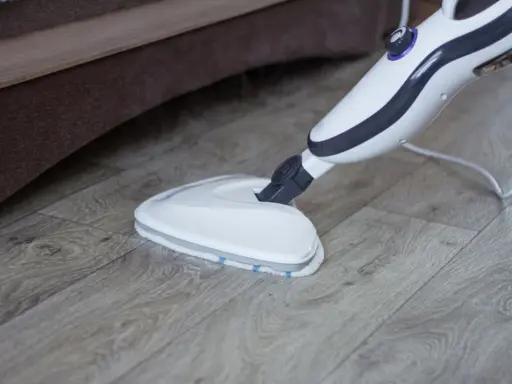 Mop parowy Vileda czyści drewnianą podłogę, wydzielając parę.