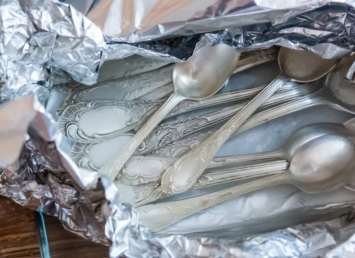 Stare, ozdobne sztućce ze srebra, schowane w folii aluminiowej. Zastanawiasz się, czym czyścimy srebro, by odzyskało blask?